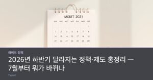 A wall calendar marked mid-year beside a stack of coins and a child's piggy bank on a bright desk