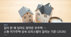 Two miniature model houses of clearly different sizes beside a small ring of keys and a magnifying glass on a bright wooden tabletop