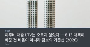A detailed architectural scale model of a tall new apartment tower standing beside a smaller model of an old low-rise house on a wooden table