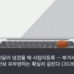 A closed silver laptop beside a short stack of coins and a red ink pad with a wooden personal seal, bright daylight desk